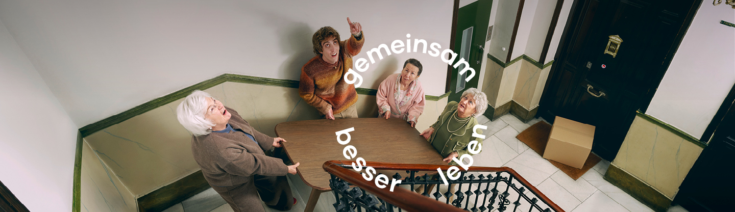 Ältere Damen und Mann tragen einen Tisch die Treppen hoch