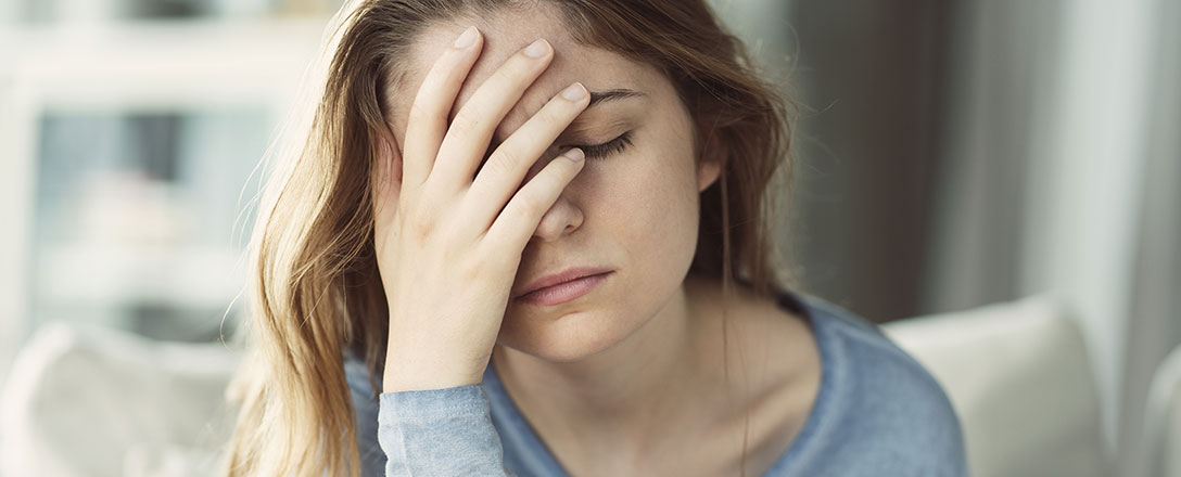 Frau greift sich erschöpft an den Kopf