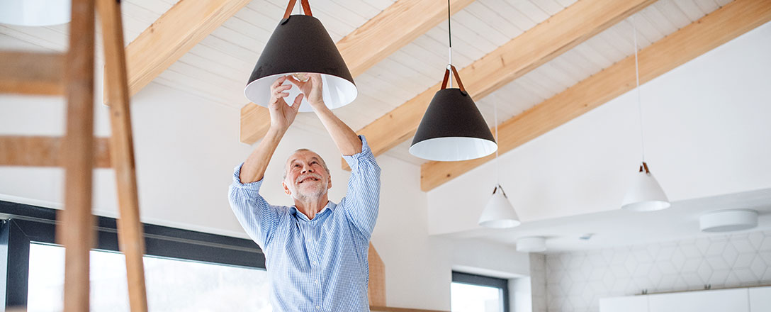 Senior tauscht Gluehbirne einer schwarzen Lampe