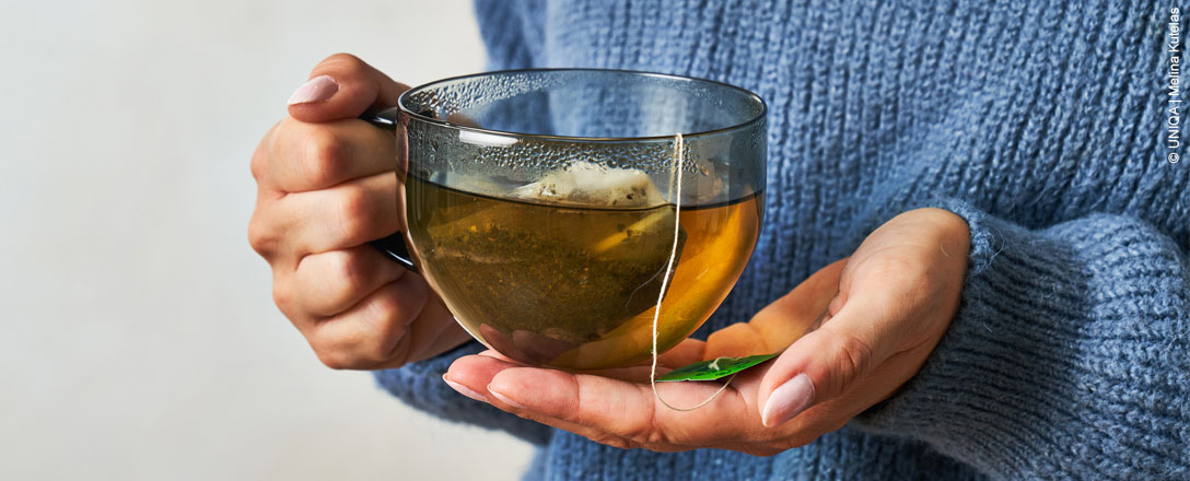 Person hält Tasse mit Tee in Händen